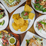 A variety of latin food on plates on a wooden table.