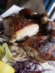 Close-up of roasted chicken pieces served on a bed of shredded red and green cabbage, garnished with lemon wedges.